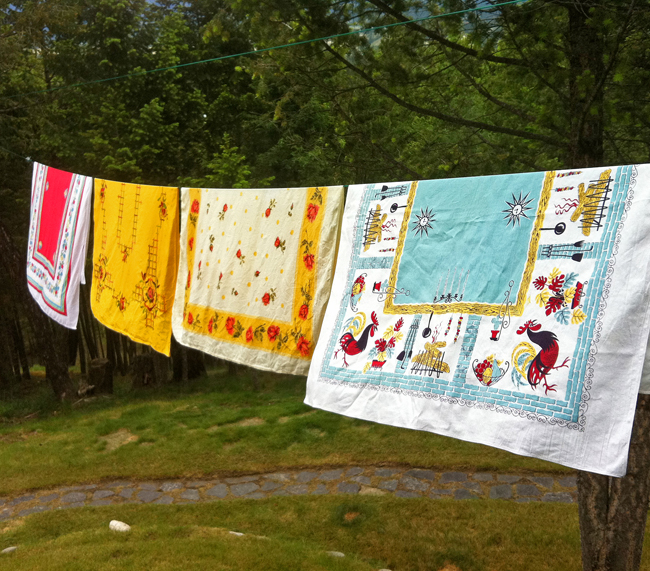 Row of colourful printed tablecloths hanging on a clothesline.