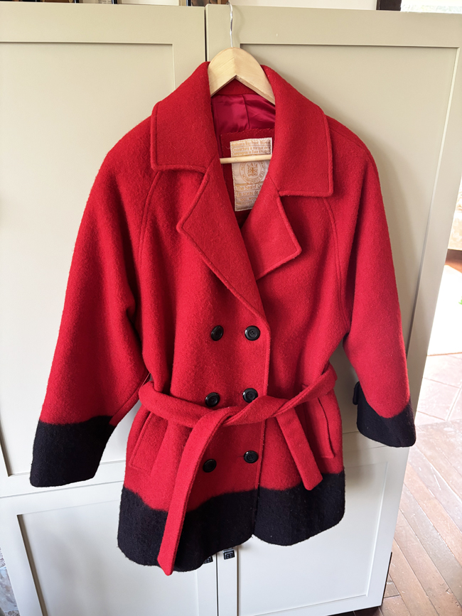Red woollen hip-length coat with black trim and buttons