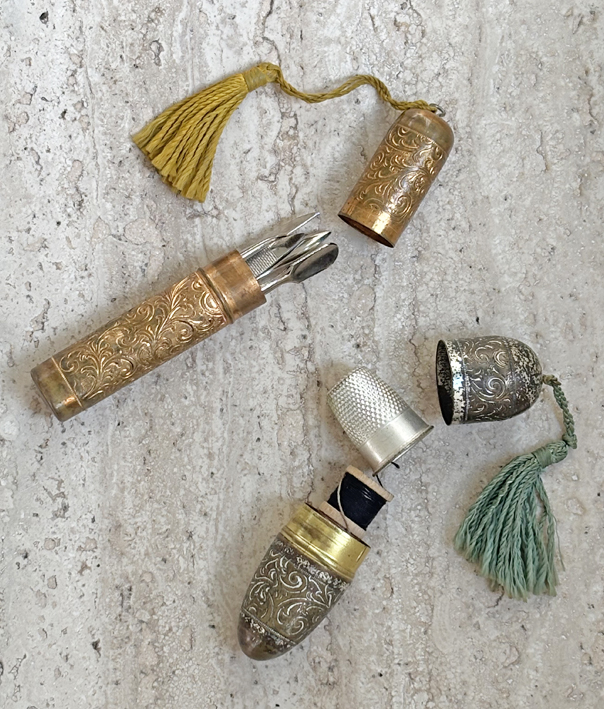 Tiny gold filigreed tube holds manicure set, and silver filigreed tube holds sewing kit.
