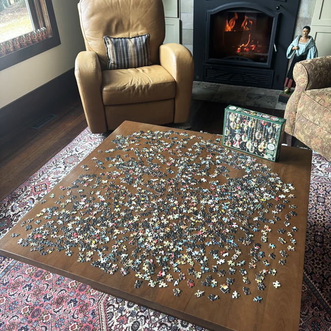 Jigsaw puzzle in one thousand pieces spread out on table before a roaring fire in the fireplace