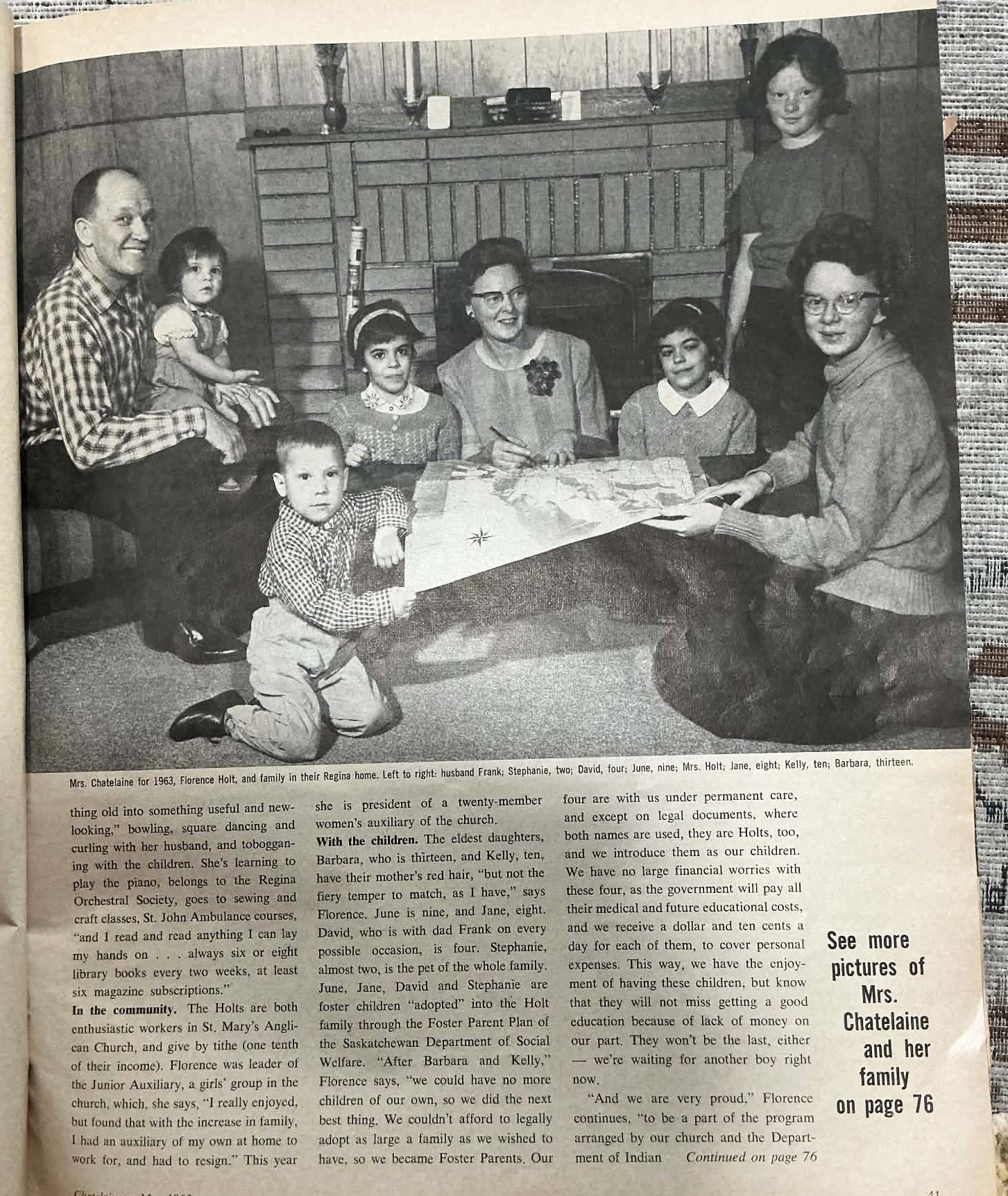Vintage newspaper photo of large family seated in front of fireplace looking at magazine