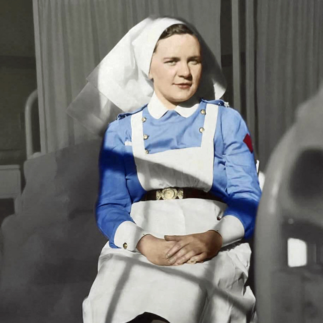 Attractive dark-haired woman in blue nursing uniform with white cowl and apron